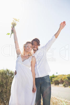 Attractive couple standing with arms raised by the road Attractive couple standing with arms raised by the road