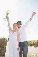 Attractive couple standing with arms raised by the road