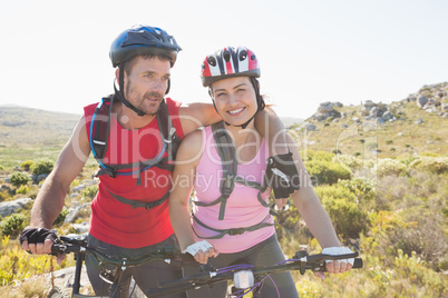 Fit cyclist couple smiling together on mountain trail