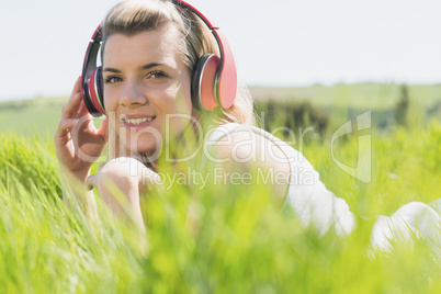 Pretty blonde lying on grass listening to music