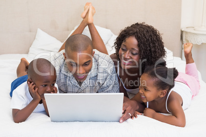 Happy family using laptop together on bed