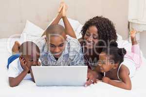 Happy family using laptop together on bed