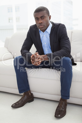 Serious businessman looking at camera on couch