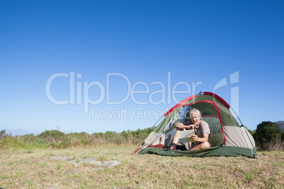 Happy camper looking at map sitting in his tent