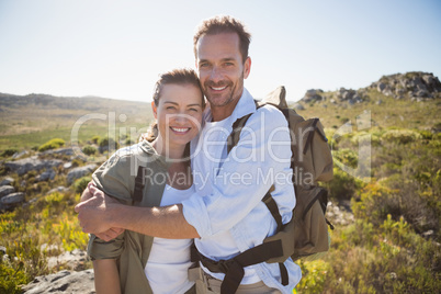 Hiking couple embracing and smiling at camera