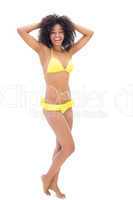 Fit girl in yellow bikini smiling at camera