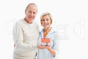 Happy mature couple with model house