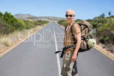 Handsome hiker walking on road and smiling at camera