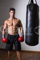 Muscular boxer with punching bag in gym