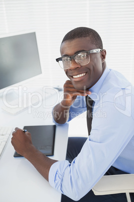 Hipster businessman smiling at camera at his desk