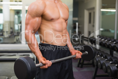 Mid section of shirtless muscular man lifting barbell