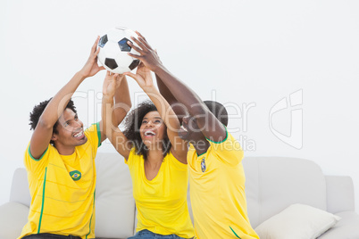 Brazil football fans sitting on couch holding ball