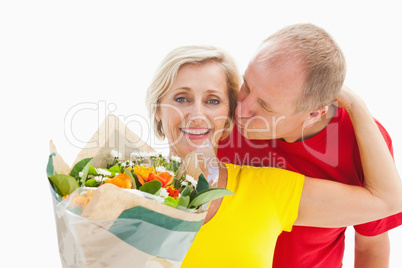 Mature man kissing his partner holding flowers