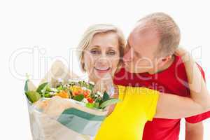 Mature man kissing his partner holding flowers