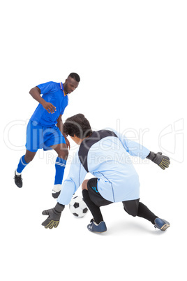 Football player in blue striking at keeper