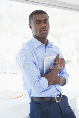 Serious businessman holding tablet pc looking at camera