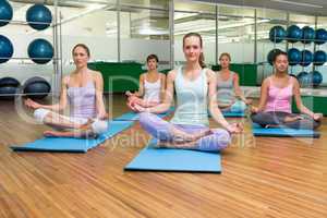 Smiling yoga class in lotus pose in fitness studio