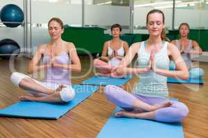 Smiling yoga class in lotus pose in fitness studio
