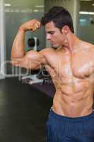 Muscular man flexing muscles in gym