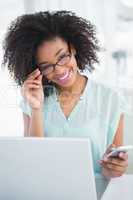 Happy businesswoman working on laptop sending a text