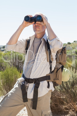 Hiker looking through binoculars on country trail