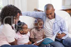 Happy family sitting on couch together reading book