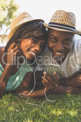 Happy couple lying in garden together listening to music