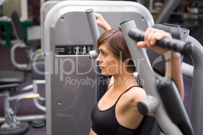 Athletic brunette using weights machine for arms