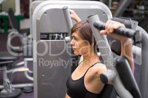 Athletic brunette using weights machine for arms