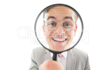 Geeky businessman looking through magnifying glass