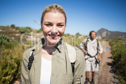 Hiking couple walking on mountain terrain woman smiling at camer