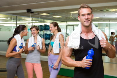 Fit man smiling at camera in busy fitness studio