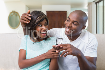 Man surprising his girlfriend with an engagement ring on the cou