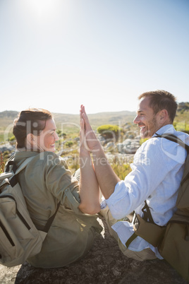 Hiking couple sitting on mountain terrain high fiving