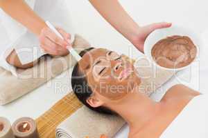 Peaceful brunette getting a mud treatment facial