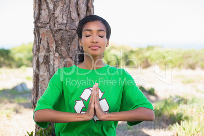 Pretty environmental activist doing yoga by a tree