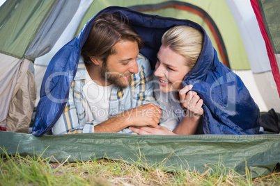 Attractive couple lying in their tent smiling at each other