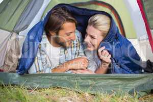 Attractive couple lying in their tent smiling at each other