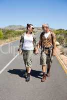 Hitch hiking couple holding hands on the road