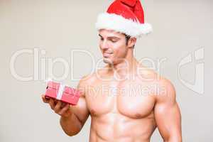 Macho man in santa hat holding gift over white background