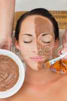 Peaceful brunette getting a mud facial applied