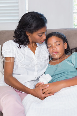 Concerned mother cuddling sick daughter