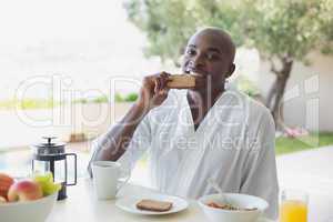 Handsome man in bathrobe having breakfast outside