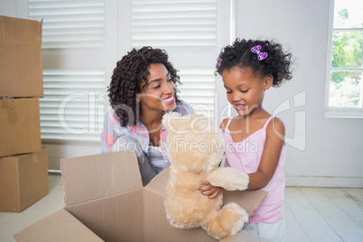Cute daughter unpacking her teddy bear with mother