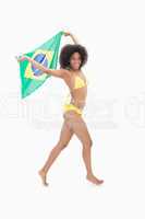Athletic girl in yellow bikini holding brazil flag