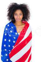 Pretty girl wrapped in american flag smiling at camera