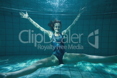 Athletic swimmer posing for camera and smiling underwater