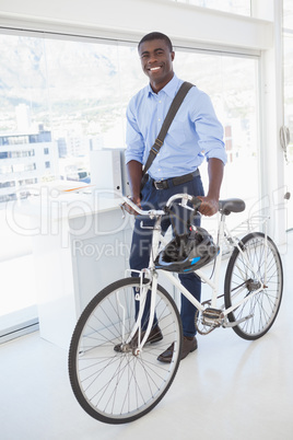 Happy businessman standing with his bike