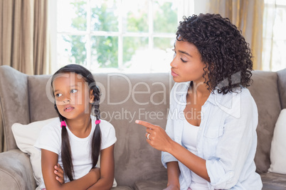 Pretty mother sitting on couch scolding her daughter