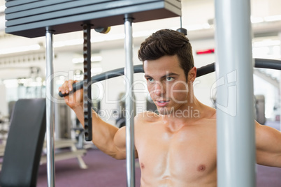 Muscular man exercising on a lat machine in gym